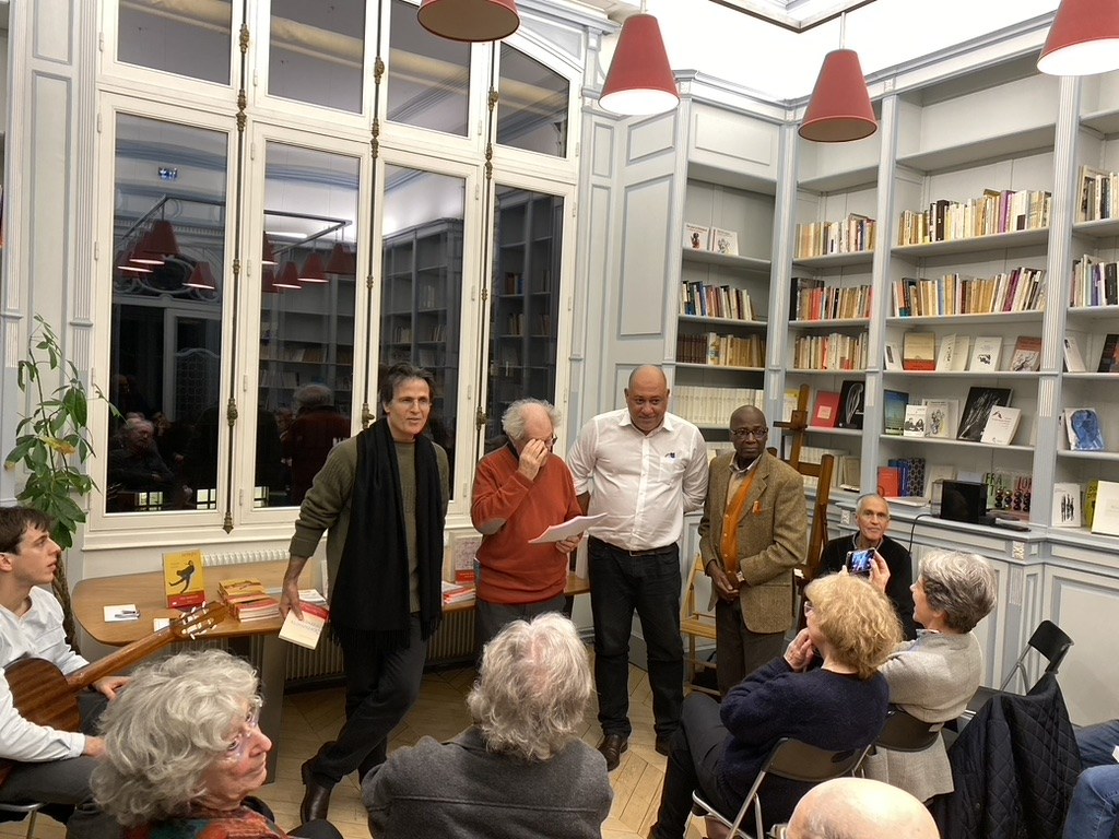 Participants à la soirée de remise des prix devant les bibliothèques de la Maison de Poésie